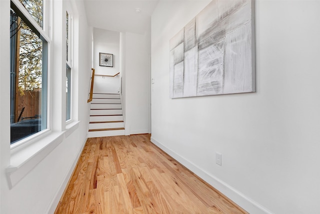 hall featuring wood finished floors, stairs, and baseboards