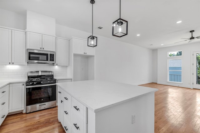 kitchen with appliances with stainless steel finishes, backsplash, light wood finished floors, recessed lighting, and open floor plan