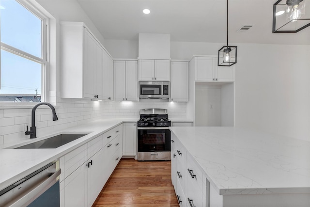 kitchen featuring stainless steel appliances, a sink, tasteful backsplash, plenty of natural light, and recessed lighting