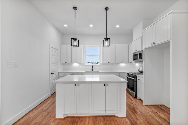 kitchen with range with gas cooktop, a sink, stainless steel microwave, decorative backsplash, and light wood-style floors