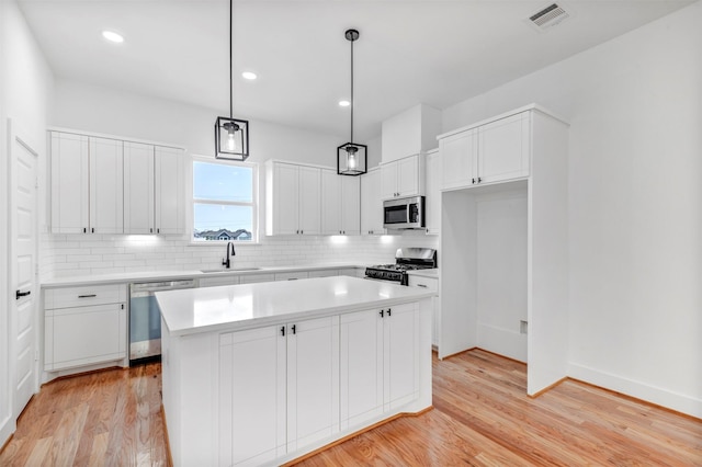 kitchen featuring appliances with stainless steel finishes, a sink, light wood finished floors, backsplash, and recessed lighting