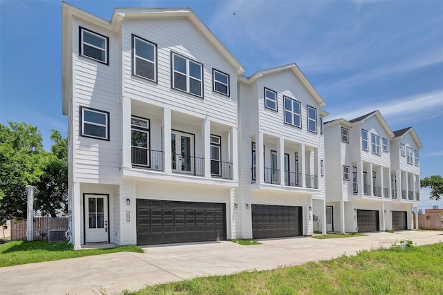 view of property featuring an attached garage, fence, concrete driveway, and a balcony