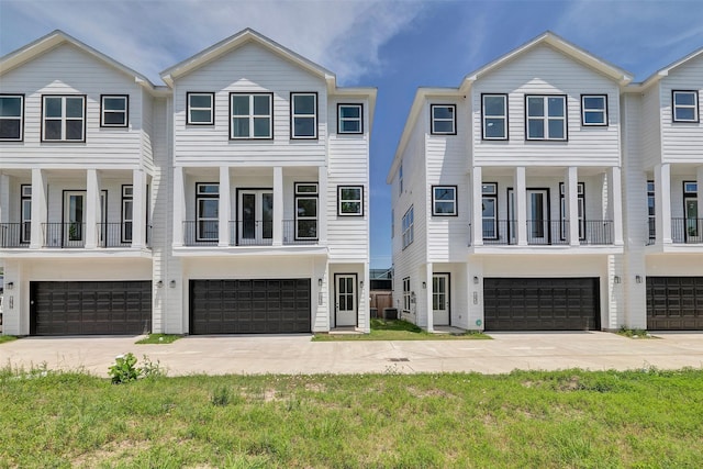 multi unit property with an attached garage, central AC unit, and concrete driveway