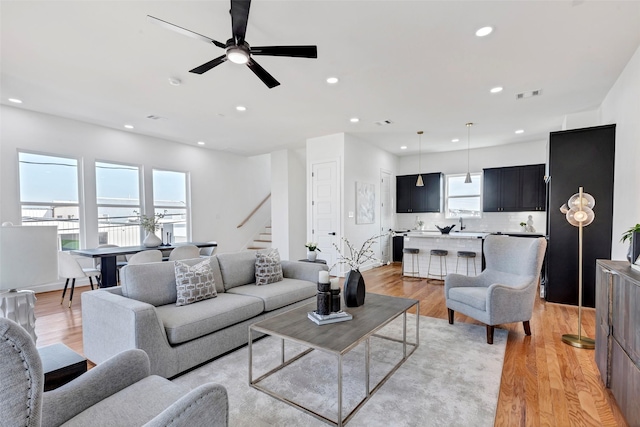 living room with stairs, light wood-style floors, recessed lighting, and a ceiling fan