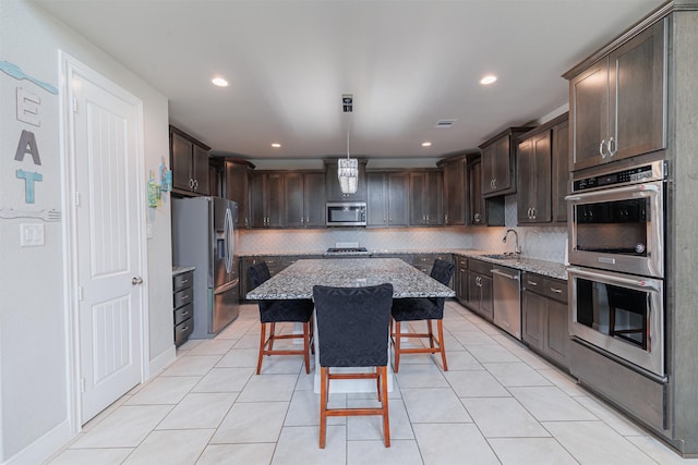 3514 Hampton Landing Ct, Katy, TX 77494 - kitchen with appliances with stainless steel finishes, dark brown cabinetry, light stone counters, a sink, and decorative backsplash