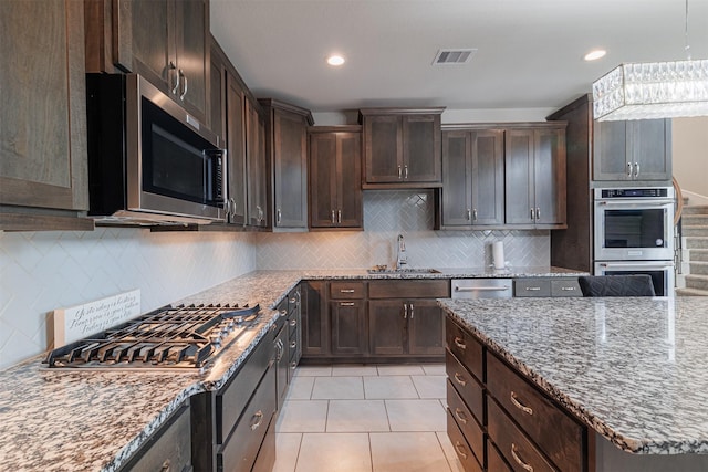 3514 Hampton Landing Ct, Katy, TX 77494 - kitchen with appliances with stainless steel finishes, a sink, dark brown cabinetry, light stone countertops, and recessed lighting