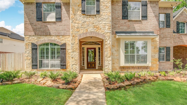 entrance to property with stone siding and fence