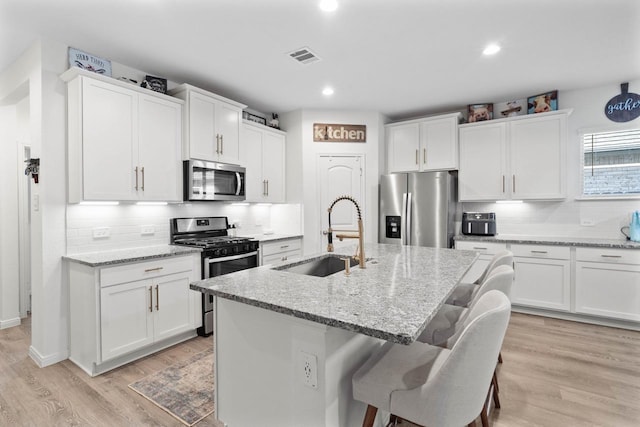 1526 Oakdale Crest Rd, Montgomery, TX 77316 - kitchen featuring stainless steel appliances, a sink, backsplash, a breakfast bar, and a center island with sink