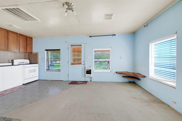 116 Linda St, Anahuac, TX 77514 - kitchen with white range with gas stovetop, heating unit, brown cabinetry, decorative backsplash, and carpet