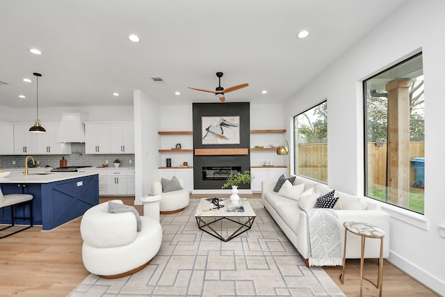 5520 Chapman St, Houston, TX 77009 - living area with recessed lighting, light wood-type flooring, a ceiling fan, a glass covered fireplace, and baseboards
