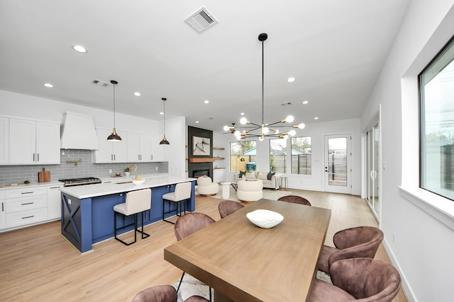 5520 Chapman St, Houston, TX 77009 - dining space with healthy amount of natural light, recessed lighting, light wood-type flooring, a chandelier, and a fireplace