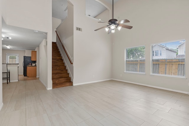 14502 Windmill Meadows Ct, Houston, TX 77082 - unfurnished living room featuring ceiling fan, stairs, a high ceiling, and baseboards