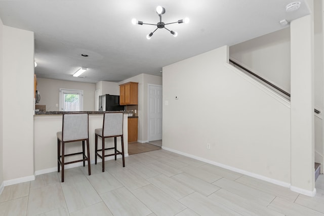 14502 Windmill Meadows Ct, Houston, TX 77082 - kitchen featuring a kitchen breakfast bar, freestanding refrigerator, a chandelier, a peninsula, and brown cabinetry