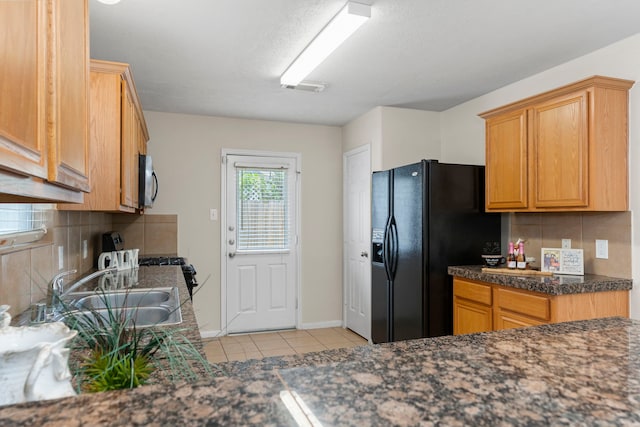 14502 Windmill Meadows Ct, Houston, TX 77082 - kitchen featuring black refrigerator with ice dispenser, light tile patterned floors, stainless steel microwave, a sink, and decorative backsplash