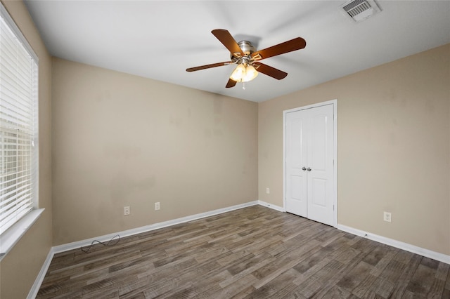 empty room with wood finished floors, a ceiling fan, and baseboards