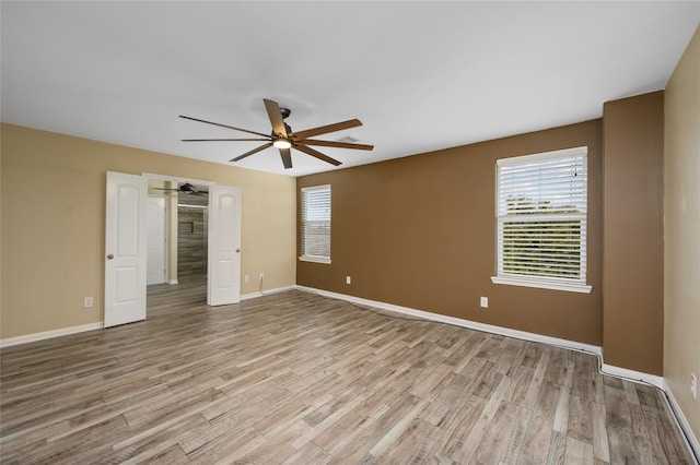 unfurnished bedroom with light wood-type flooring, multiple windows, baseboards, and ceiling fan