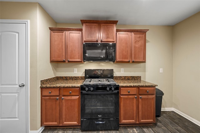 kitchen with black appliances, dark wood-style floors, baseboards, dark stone counters, and brown cabinetry