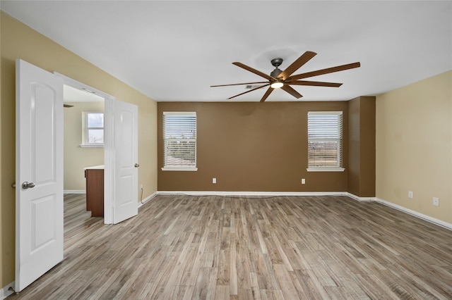 unfurnished room featuring ceiling fan, light wood-style floors, and baseboards