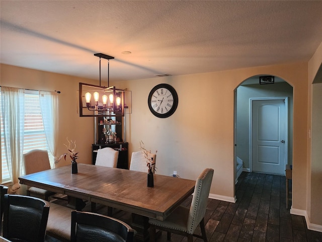 dining space featuring a chandelier, dark wood-type flooring, arched walkways, and baseboards