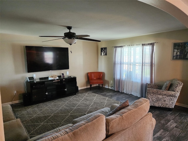 living room featuring baseboards, arched walkways, dark wood-style floors, and ceiling fan