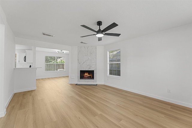 unfurnished living room with light wood finished floors, healthy amount of natural light, and baseboards