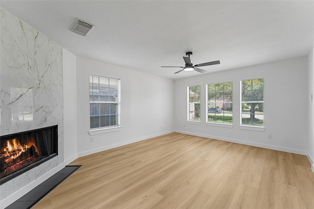 unfurnished living room with light wood-type flooring, a fireplace, and baseboards