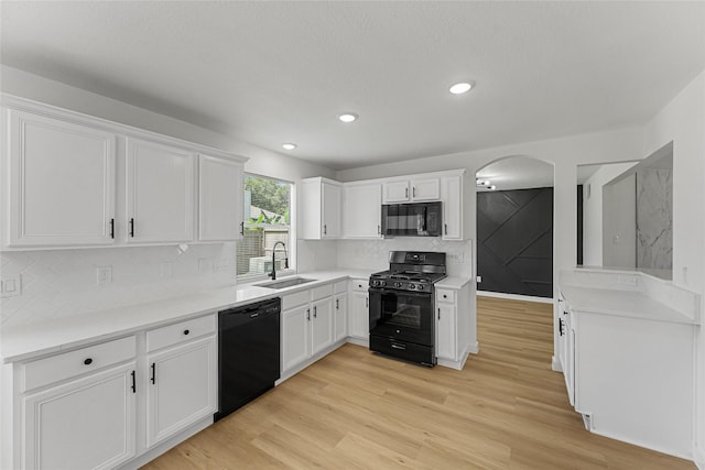 kitchen with black appliances, a sink, white cabinets, and recessed lighting