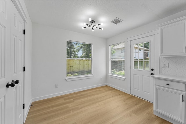 doorway with light wood-style floors, baseboards, and a chandelier