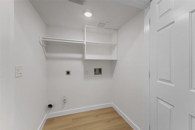 clothes washing area featuring hookup for an electric dryer, washer hookup, baseboards, hookup for a gas dryer, and light wood finished floors