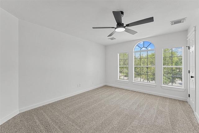 carpeted spare room featuring baseboards and a ceiling fan