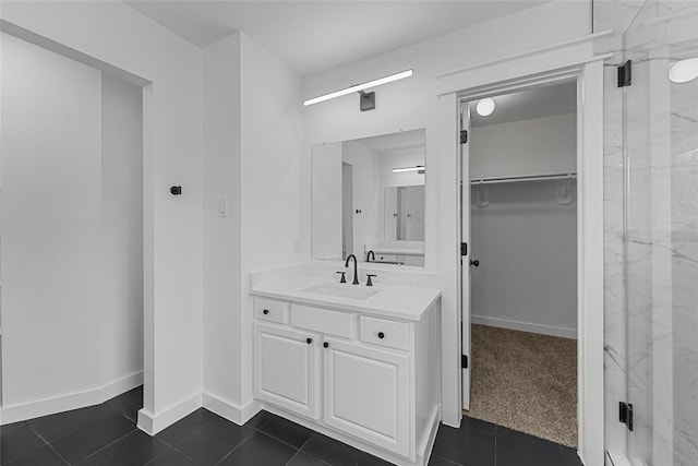 full bath with a walk in closet, a marble finish shower, vanity, tile patterned flooring, and baseboards
