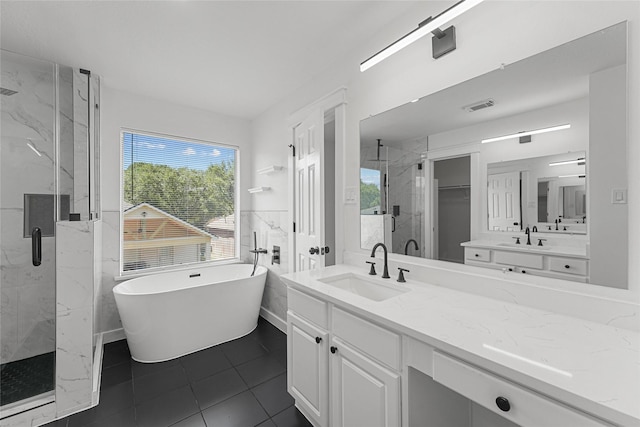 full bath with a marble finish shower, a freestanding tub, vanity, and tile patterned floors
