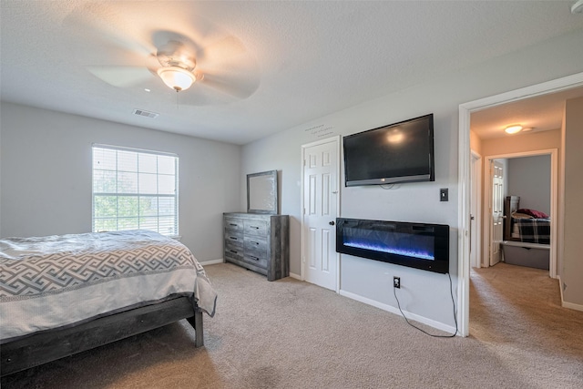 2202 Megellan Point Ln, Pearland, TX 77584 - bedroom with light carpet, a glass covered fireplace, baseboards, and a textured ceiling