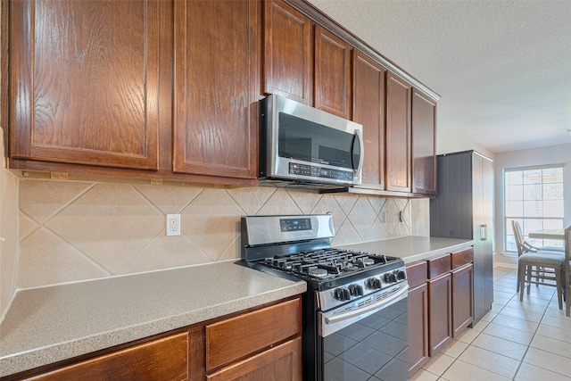 2202 Megellan Point Ln, Pearland, TX 77584 - kitchen featuring appliances with stainless steel finishes, decorative backsplash, light tile patterned floors, light countertops, and a textured ceiling