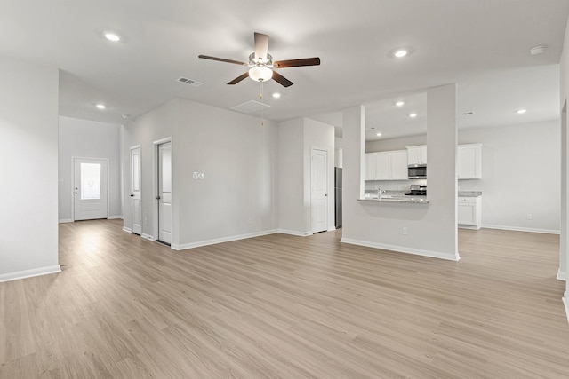 10811 Bright Beacon Dr, Beasley, TX 77417 - unfurnished living room featuring a ceiling fan, light wood-style floors, baseboards, recessed lighting, and a sink