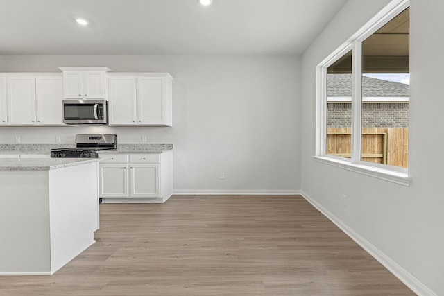 10811 Bright Beacon Dr, Beasley, TX 77417 - kitchen with stainless steel appliances, baseboards, white cabinets, light wood finished floors, and recessed lighting