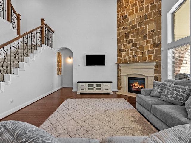 913 Ember Hills Ln, Friendswood, TX 77546 - living room with a towering ceiling, arched walkways, dark wood-style floors, baseboards, and a large fireplace