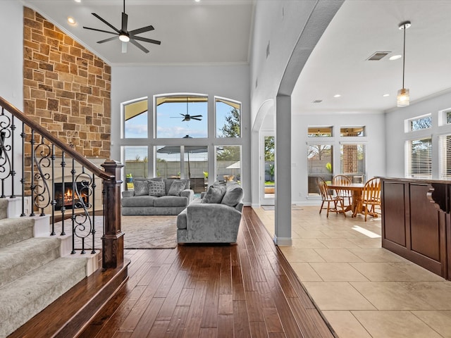913 Ember Hills Ln, Friendswood, TX 77546 - living room featuring ceiling fan, ornamental molding, arched walkways, stairs, and high vaulted ceiling