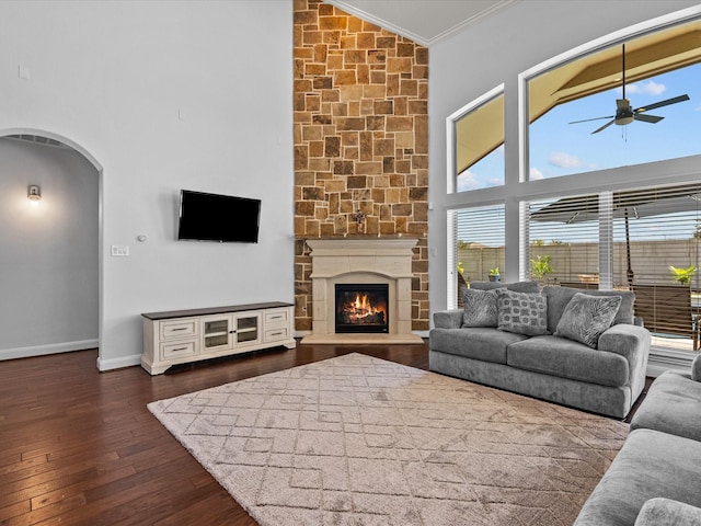 913 Ember Hills Ln, Friendswood, TX 77546 - living area with crown molding, a ceiling fan, dark wood-style flooring, arched walkways, and a stone fireplace