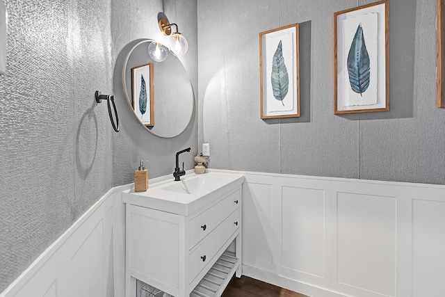 22802 Pennyrile Ln, Katy, TX 77450 - bathroom with a decorative wall, vanity, a wainscoted wall, wood finished floors, and a textured wall