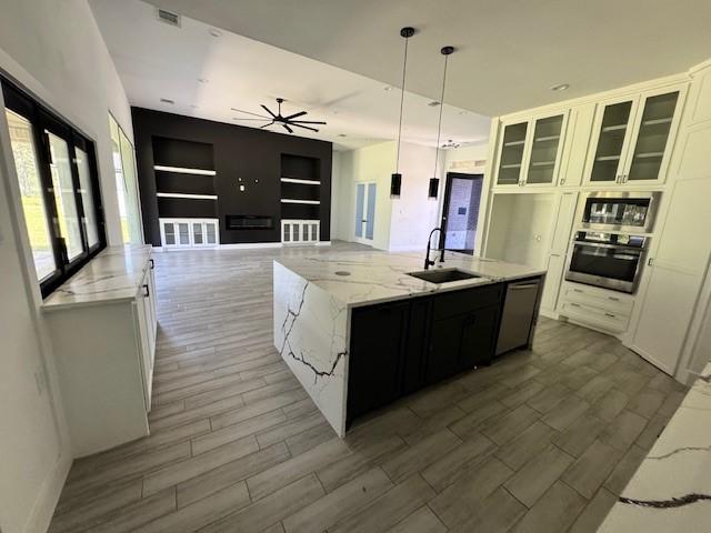 409 Rd 66111, Dayton, TX 77535 - kitchen featuring appliances with stainless steel finishes, a sink, wood finished floors, a ceiling fan, and light stone counters