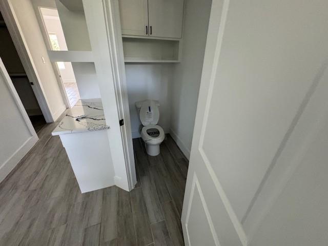409 Rd 66111, Dayton, TX 77535 - bathroom with wood finished floors, baseboards, and toilet