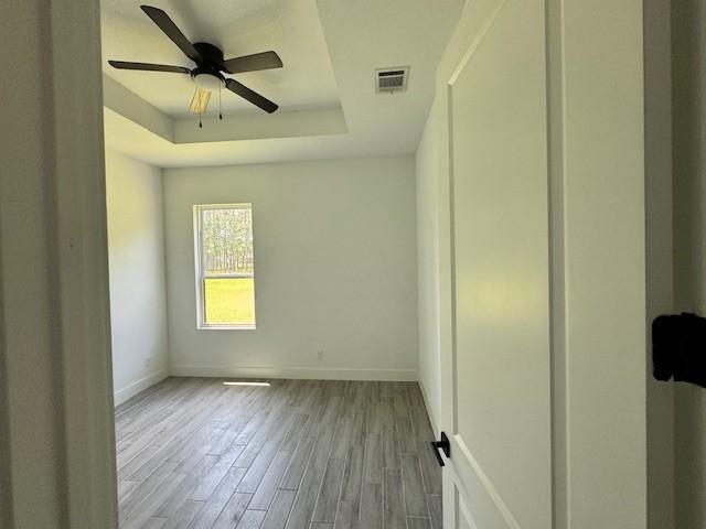 409 Rd 66111, Dayton, TX 77535 - empty room featuring a tray ceiling, baseboards, wood finished floors, and a ceiling fan