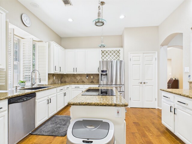 4210 Rock Springs Dr, Houston, TX 77345 - kitchen with stainless steel appliances, a sink, arched walkways, decorative backsplash, and white cabinetry