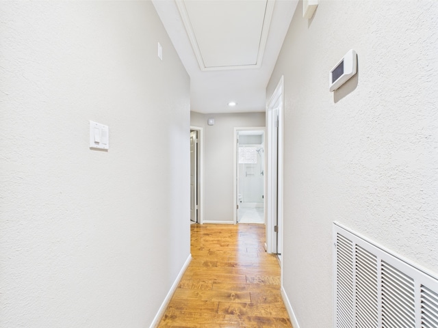 4210 Rock Springs Dr, Houston, TX 77345 - hallway with light wood-type flooring, attic access, baseboards, and a textured wall