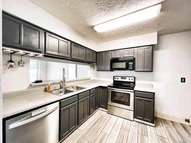 21510 N Tangle Creek Ln, Spring, TX 77388 - kitchen with appliances with stainless steel finishes, a sink, a textured ceiling, wood finish floors, and light countertops