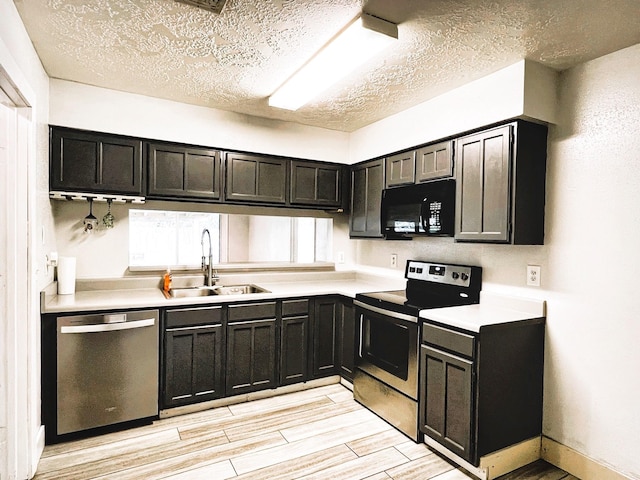 21510 N Tangle Creek Ln, Spring, TX 77388 - kitchen with appliances with stainless steel finishes, a sink, light countertops, dark cabinetry, and light wood-style floors