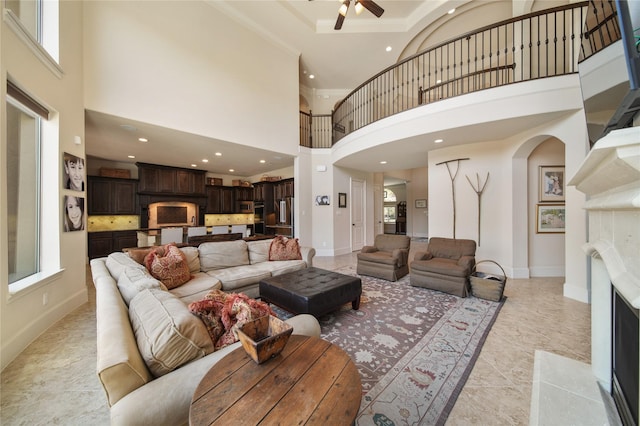 7106 Sentinel Fls, Missouri City, TX 77459 - living area with arched walkways, ceiling fan, a fireplace with flush hearth, healthy amount of natural light, and a high ceiling