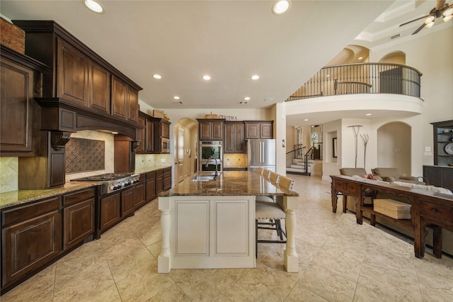 7106 Sentinel Fls, Missouri City, TX 77459 - kitchen with stainless steel appliances, a sink, arched walkways, dark stone countertops, and tasteful backsplash