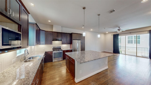1913 Hickory St, Houston, TX 77007 - kitchen with stainless steel appliances, a sink, a center island, decorative backsplash, and under cabinet range hood